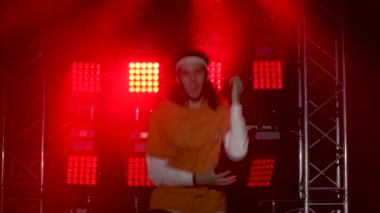 Stüdyoda modern dans gösterisi yapan profesyonel hip-hop dansçısının portresi hareketlere yoğunlaşmıştı. Halk ve gençlik kültürü kavramı. Dinamik kırmızı ışık efektleri. Kapat.