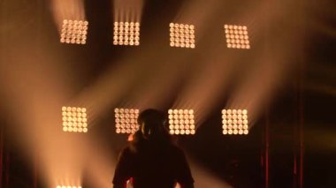 Genç bir adamın silueti modern stüdyoda tek başına dans ederek karanlık odada breakdance gösterisi yapıyor. İnsanlar, kültür ve yaşam tarzı konsepti. Kapat..