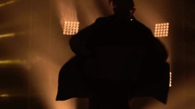 Genç bir adamın silueti modern stüdyoda tek başına dans ederek karanlık odada breakdance gösterisi yapıyor. İnsanlar, kültür ve yaşam tarzı konsepti. Kapat..