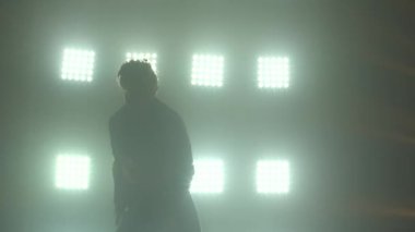 Erkek dansçı hip hop dansı yapıyor. Şehir dansçısı. Modern dans kültürü. Sahne ışıkları önünde şık bir adamın koyu bir silueti. Kapat..