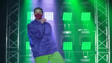 Koruyucu tıbbi maskeli yetenekli hip hop dansçısı. Karanlık bir stüdyoda, dumanlı ve neon ışıklı bir sahnede hip hop sokak dansı. Sağlıklı ve aktif yaşam tarzı konsepti. Kapat..