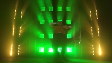 Neşeli adam hip hop yapıyor ve dansın tadını çıkarıyor. Dinamik yeşil spot ışıklarıyla karanlık dumanlı bir stüdyoda çekildi..