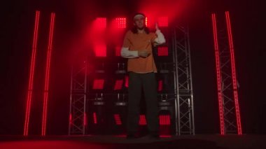 Karanlık stüdyoda dans eden genç adam duman ve kırmızı neon ışıkla. Hip hop ve break dans tekniği öğrenme kavramı. Gençlik alt kültürü. Çağdaş koreografi.