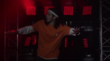 Stüdyoda modern dans gösterisi yapan profesyonel hip-hop dansçısının portresi hareketlere yoğunlaşmıştı. Dinamik çok renkli ışıklandırma efektleri. Yaklaş. Yavaş çekim.