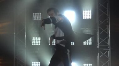 Modern dans eden eşofmanlı yetenekli çocuk. Genç adam stüdyoda hip-hop yapıyor. Çağdaş dansın dersi. Dumanlı ve neon ışıklı karanlık stüdyo. Kapatın. Yavaş çekim.