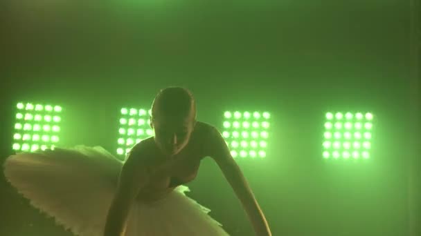 Professionell ballerinadansbalett i spotlights och rök på stora scenen. Smal siluett av en vacker ung flicka bär vit tutu klänning på strålkastare bakgrund. Närbild. — Stockvideo