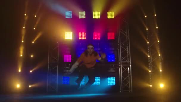 Young guy dancing street dance in in dark studio with smoke and multicolored neon lighting. Concept of learning hip hop and break dance technique. Youth subculture. Contemporary choreography. — Stock Video