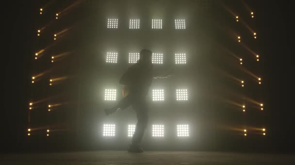 Karanlık stüdyoda hip-hop dansı yapan çekici bir adam, neon ışığı, bolca duman. Modern dans gösterisi yapan şık kıyafetli şirin bir adamın silueti. Ritmi hisset.. — Stok video
