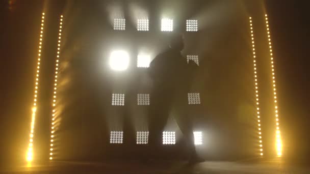 Tinédzser sziluettje alkalmi kolbászban improvizál a fekete stúdióban. Sötét stúdió füsttel és neon világítással. Alkotói készségek. — Stock videók