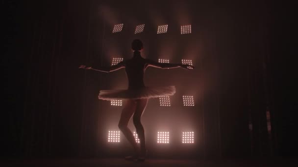 优雅勤劳的芭蕾舞演员穿着白衣在演播室里跳舞，背景是黑色的。勤勉的芭蕾舞演员表演古典芭蕾舞中的舞蹈元素. — 图库视频影像