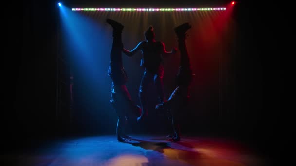 De groep acrobaat gymnastiek mannen op balans poseren. Een moeilijke acrobatische stunt uitgevoerd in een studio met neon licht. Langzame beweging. — Stockvideo