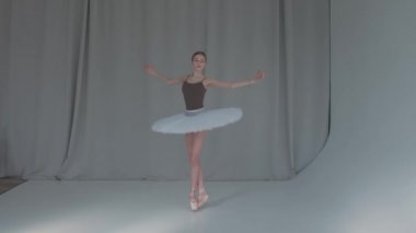 Genç, gelecek vaat eden bir balerin klasik bir bale dansı yapıyor. Geniş, parlak bir stüdyoda, arka planda perdelerle çekilmiş. Yavaş çekim.