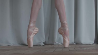 Balerin bacakları yakın. Sivri uçlu bale ayakkabılarıyla dans ediyor. Parlak ve güneşli bir stüdyoda çekilmiş. Yavaş Hareket.