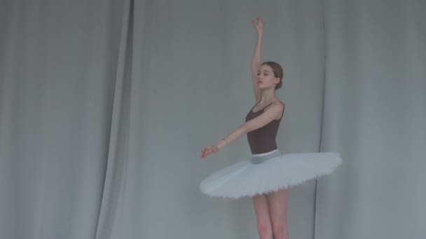 Kvinnlig dansare balett på en ljus bakgrund utför mjuka rörelser med händerna. Graciös repetition av den vita svanens del i en rymlig sal. Närbild. Långsamma rörelser. — Stockvideo