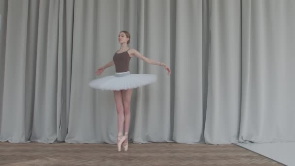 Tender ballerina dans in een balletschool van klassieke dans. Opgenomen in de studio met lange gordijnen en parketvloeren op de achtergrond. Langzame beweging. — Stockvideo