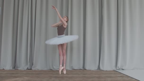 Нежный танец балерины в балетной школе классического танца. Съемка в студии с длинными шторами и паркетными полами на заднем плане. Медленное движение. — стоковое видео