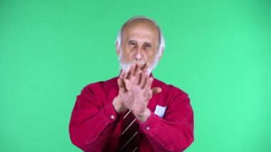 70 'li yaşlarda mutlu yaşlı bir adamın portresi. Elleri çaprazlanmış bir şekilde el kol hareketi yapıyor. X şekli, inkar anlamına geliyor..