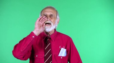 70 'li yaşların mutlu, yaşlı bir adamın portresi yeşil arka planda izole edilmiş birini çağırıyor..