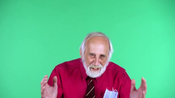 Portret van een gelukkige oude man uit de 70 die naar de camera keek en de overwinning vierde, geïsoleerd over een groene achtergrond. — Stockvideo
