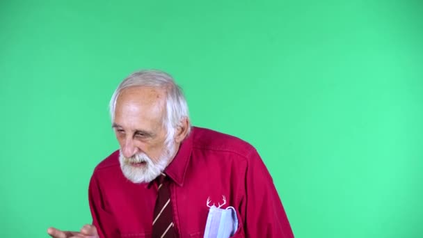 Portrait of happy old aged man 70s communicates with someone, isolated over green background. — Stock Video