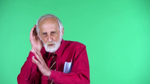 Retrato de velhote feliz 70 anos segurando a mão perto do ouvido tentando ouvir notícias expressando conceito de comunicação e fofocas. Tela verde — Vídeo de Stock