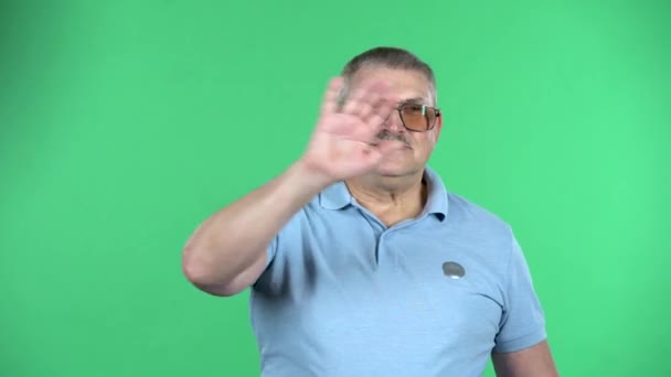 Portrait of aged man waving his hand and showing gesture come here, isolated over green background. — Stock Video