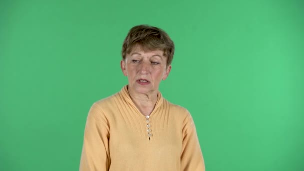 Retrato de mulher idosa está focada pensando em algo, sem ideia, isolado sobre fundo verde. — Vídeo de Stock