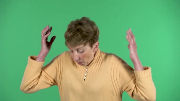 高齢者の女性の肖像画、憤りで手を振って、緑の背景に隔離されて動揺している. — ストック動画