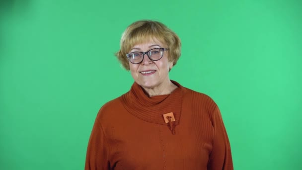 Portrait of senior woman is looking straight and smiling isolated over green background. — Stock Video