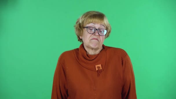 Портрет старшої жінки дивиться прямо і відгинається ізольовано на зеленому тлі . — стокове відео