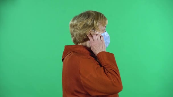 Старша жінка знімає свою медичну одноразову маску і робить глибокий подих, ізольований на зеленому тлі . — стокове відео