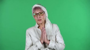 Yeşil arka planda çok şaşırmış ve mutlu bir şekilde izole olmuş yaşlı stil sahibi bir kadının portresi..