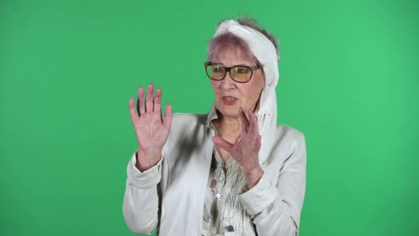 Portrait of old stylish woman is surprised and shocked by what she saw isolated over green background. — Stock Video