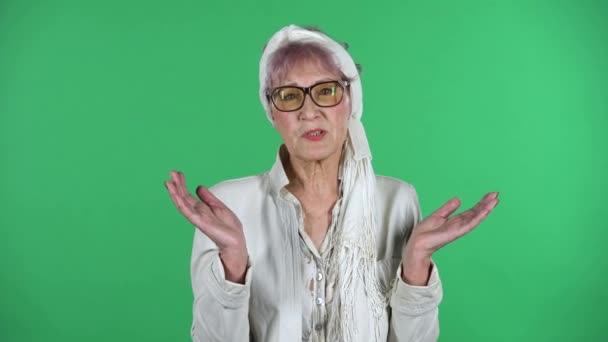 Portrait of old stylish woman is communicates with someone frustrated isolated over green background. — Stock Video