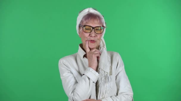 Portrait of old stylish woman is communicates with someone in a friendly manner isolated over green background. — Stock Video