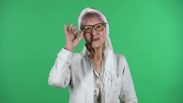 Portrait of old stylish woman is making sign ok isolated over green background. — Stock Video