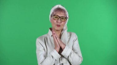 Yaşlı stil sahibi kadının portresi, yeşil arka planda soyutlanmış kollarıyla şefkatle bakıyor..