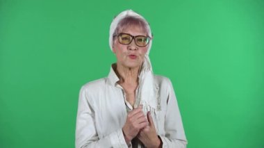 Yaşlı ve şık bir kadının portresi yeşil arka planda izole edilmiş..