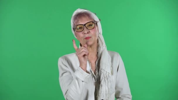 Retrato de la vieja mujer con estilo se comunica con alguien de una manera amistosa aislado sobre fondo verde. — Vídeos de Stock