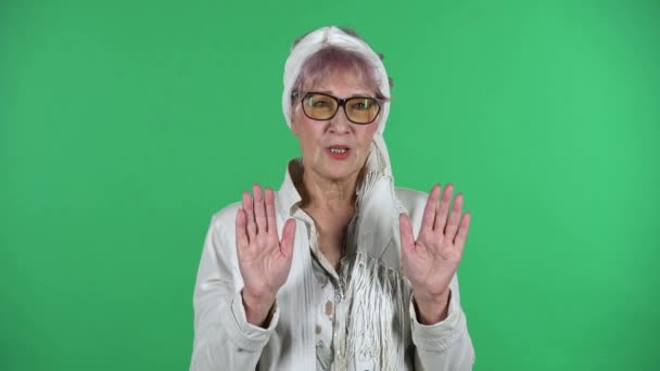 Retrato de la vieja mujer con estilo está rechazando el estrés y tomando la situación, calmándose, respirando profundamente aislado sobre el fondo verde. — Vídeos de Stock