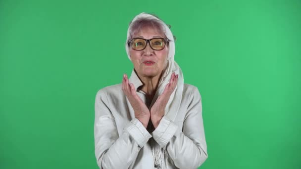 Portrait of old stylish woman is communicates with someone in a friendly manner isolated over green background. — Stock Video