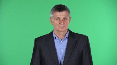 Yaşlı bir adamın portresi, yeşil arka planda izole edilmiş öfkeyle ellerini sallıyor..