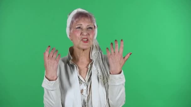 Ritratto di vecchia donna alla moda sta dicendo un sacco di informazioni interessanti isolato su sfondo verde. — Video Stock