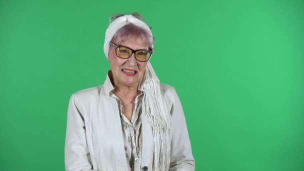 Portrait of old stylish woman is indignantly talking to someone, isolated over green background. — Stock Video