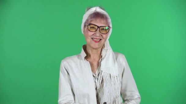 Portrait of old stylish woman is looking straight and smiling isolated over green background. — Stock Video