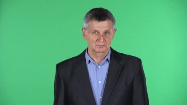 Yaşlı bir adamın portresi. Yeşil arka planda izole edilmiş bir jest..