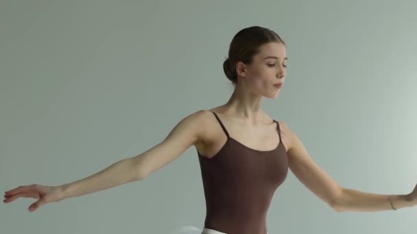 Una atractiva bailarina joven está bailando elementos del ballet clásico. Autopreparación para la actuación. Fondo blanco. De cerca. Movimiento lento. — Vídeos de Stock