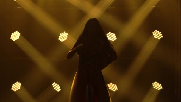 Chica bailando en un estudio oscuro con humo y luces de neón amarillo. Silueta atractiva morena en un traje sexy en el color de la bandera inglesa y diamantes de imitación. Espectáculo de danza femenina contemporánea. — Vídeos de Stock