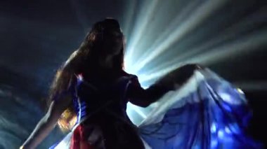 Ateşli esmer, İngiliz bayrağı ve sahte elmaslarla seksi bir takım elbise içinde dans ediyor. Karanlık ve dinamik neon ışıklardaki gece kulübü. Dumanlı bir arka plan. Siluet. Kapat..