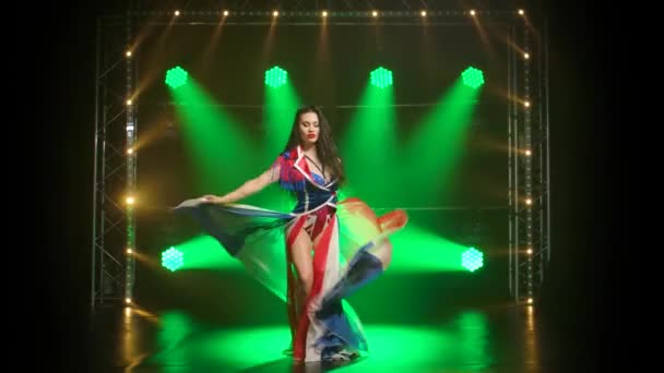Chic κορίτσι χορεύει σε ένα σέξι κοστούμι στο χρώμα της αγγλικής σημαίας και στρας. Ελκυστική μελαχρινή σε σκοτεινό στούντιο με καπνό και πράσινα φώτα νέον. Σέξι γυναικεία χορευτική παράσταση. — Αρχείο Βίντεο
